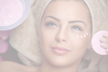 Faded background image of a woman laying down with a towel over her hair while someone is about to give her a facial.
